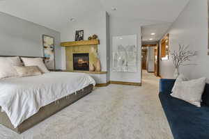 Bedroom with carpet flooring, lofted ceiling, a fireplace, baseboards, and recessed lighting