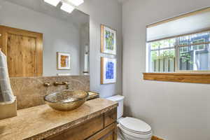 Bathroom featuring decorative backsplash, toilet, and vanity