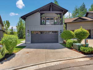 View of front of home with board and batten siding, driveway, an attached garage, and a balcony