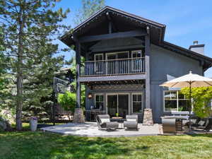 Rear view of property with a balcony, a chimney, outdoor lounge area, and a lawn