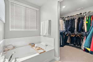 Bathroom featuring a bath and a spacious walk-in  closet