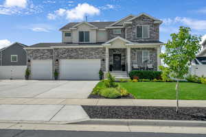 View of front facade featuring stone and stucco siding, covered porch, an attached 3 car garage and additional parking.