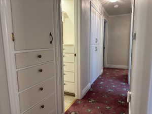 Corridor with light colored carpet, crown molding, and baseboards