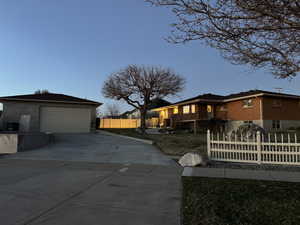 View of front facade featuring a garage, an outbuilding, a balcony, and concrete driveway