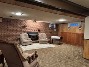 Carpeted living area featuring a wood stove, brick wall, and wood walls