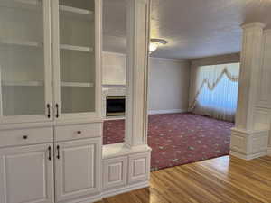 Interior space with a textured ceiling, light wood finished floors, light carpet, a fireplace, and baseboards