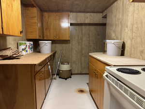 Kitchen with brown cabinetry, light countertops, finished concrete floors, and white electric range