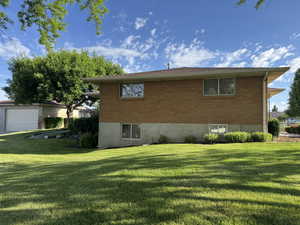 View of property exterior with a yard, brick siding, and a detached garage