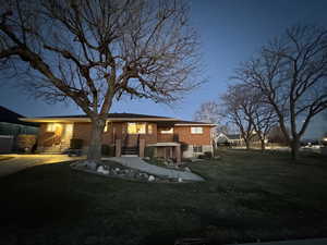 Rear view of property featuring brick siding, a lawn, and stairway