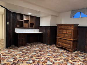 Office area with a wainscoted wall, a textured ceiling, and wood walls