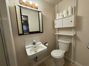 Bathroom featuring a sink, toilet, baseboards, and tile patterned flooring