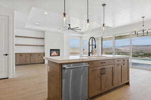 Kitchen featuring dishwasher, a chandelier, hanging light fixtures, light countertops, and an island with sink