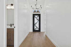 Foyer with light wood-type flooring, a chandelier, and baseboards
