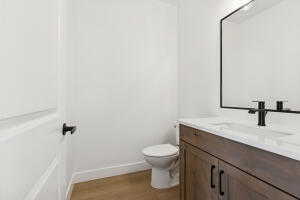 Bathroom with vanity, toilet, wood finished floors, and baseboards