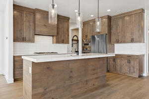 Kitchen featuring freestanding refrigerator, light wood-type flooring, light countertops, pendant lighting, and recessed lighting