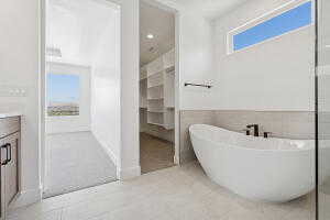 Bathroom with a freestanding tub, vanity, a walk in closet, tile walls, and recessed lighting