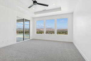 Carpeted spare room featuring a raised ceiling, a ceiling fan, and baseboards
