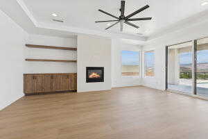 Unfurnished living room featuring wood finished floors, a lit fireplace, a raised ceiling, recessed lighting, and built in shelves