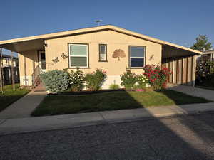 Manufactured / mobile home featuring a carport, a front lawn, and driveway