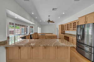 Kitchen featuring stainless steel refrigerator with ice dispenser, a sink, a peninsula, a breakfast bar area, and glass insert cabinets