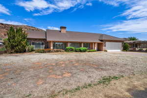 Single story home featuring a tile roof, an attached garage, a chimney, and driveway