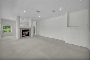 Unfurnished living room featuring carpet floors, a tile fireplace, and recessed lighting