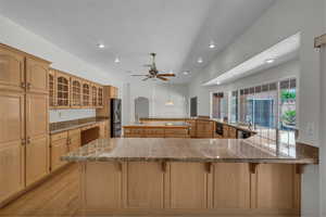 Kitchen with stainless steel fridge with ice dispenser, a kitchen breakfast bar, recessed lighting, light wood-type flooring, and a sink