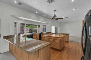 Kitchen featuring freestanding refrigerator, a sink, a peninsula, ceiling fan, and recessed lighting