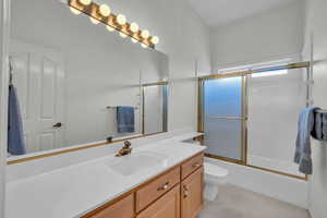 Full bath with vanity, toilet, and enclosed tub / shower combo