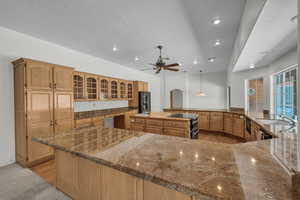 Kitchen featuring black refrigerator with ice dispenser, a large island, recessed lighting, arched walkways, and a sink