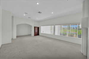 Carpeted empty room with arched walkways and recessed lighting