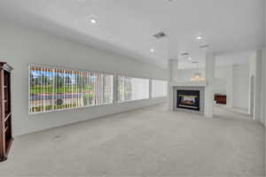 Unfurnished living room with carpet flooring, a tile fireplace, recessed lighting, baseboards, and a chandelier