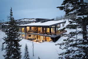 Snow covered property with stone siding