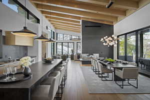 Dining room with a high ceiling, hardwood / wood-style floors, wooden ceiling with exposed beams, and healthy amount of natural light