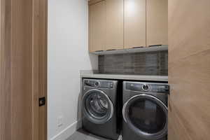 Laundry room with cabinet space, independent washer and dryer, and baseboards