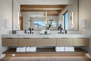 Full bathroom featuring double vanity, beamed ceiling, and healthy amount of natural light