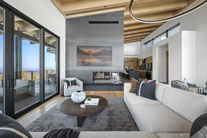 Living area with a towering ceiling, wood finished floors, and beam ceiling