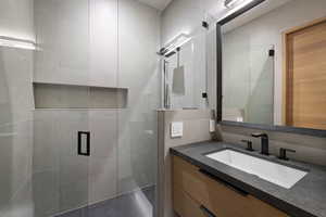 Full bathroom featuring a shower stall, vanity, and tile walls