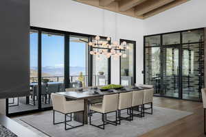 Dining area featuring a mountain view, a towering ceiling, wood finished floors, beamed ceiling, and a chandelier