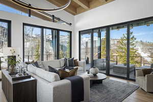 Living room with wood finished floors, a towering ceiling, and wood ceiling with exposed beams