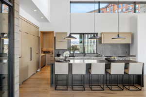 Kitchen featuring recessed lighting, backsplash, modern cabinets, a kitchen bar, and hanging light fixtures
