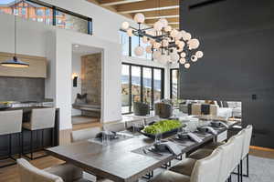 Dining room with a towering ceiling, wood finished floors, a chandelier, and beam ceiling