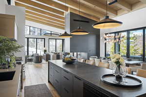 Kitchen featuring open floor plan, wooden ceiling with exposed beams, a towering ceiling, wood finished floors, and dark countertops