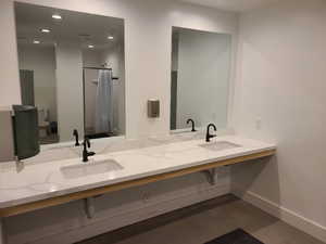 Bathroom featuring toilet, baseboards, double vanity, recessed lighting, and finished concrete flooring