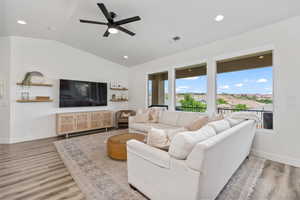 Living room with lofted ceiling, light wood-type flooring, ceiling fan, and recessed lighting
