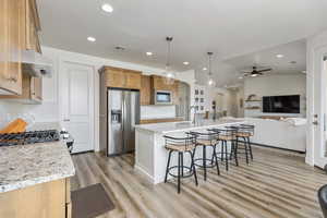 Kitchen with arched walkways, a breakfast bar, decorative light fixtures, open floor plan, and stainless steel appliances