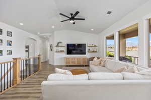 Living room with lofted ceiling, wood finished floors, ceiling fan, arched walkways, and recessed lighting