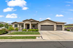 Prairie-style home with stone siding, stucco siding, a front lawn, and an attached garage