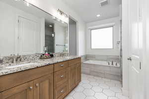 Full bath featuring double vanity, light tile patterned floors, a garden tub, a shower stall, and recessed lighting