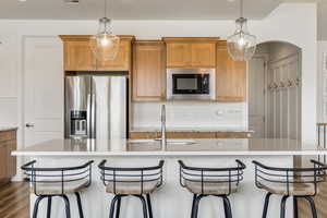 Kitchen with tasteful backsplash, stainless steel refrigerator with ice dispenser, built in microwave, and light stone counters